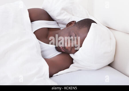 Portrait Of Young African Man Sleeping On Bed Stock Photo