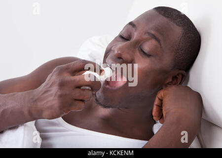 Portrait Of Young African Man Using Asthma Inhaler Stock Photo