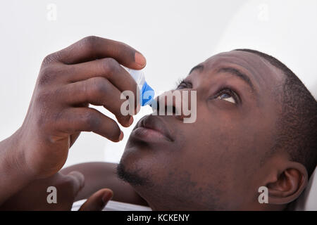 Close-up Of African Man Using Nose Spray Stock Photo