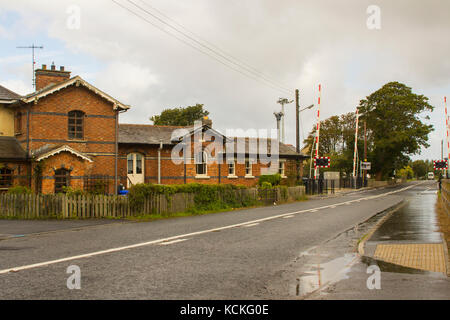 The refurbished station and automatic rail crossing at the town land of bellerena on the North coast of Ireland in County Londonderry on a dull day Stock Photo