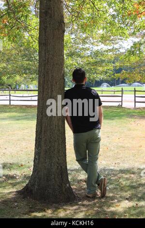 A male model thinking and leaning against a tree in the New England region of the North Atlantic part of Massachusetts Stock Photo