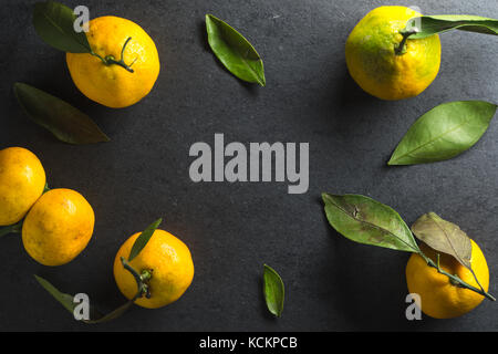 Frame of yellow mandarins with leaves on a gray background horizontal Stock Photo