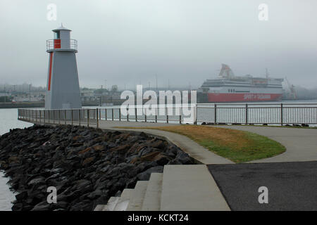 Navigation marker for boats entering the port on a gloomy day, with the Bass Strait ferry ’Spirit of Tasmania’ in the background. Devonport, Tasmania, Stock Photo