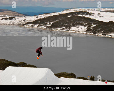 Snowboarder in mid jump above the Rocky Valley Dam, part of the Kiewa Hydroelectric Scheme. Falls Creek, Alpine National Park,Victoria, Australia Stock Photo