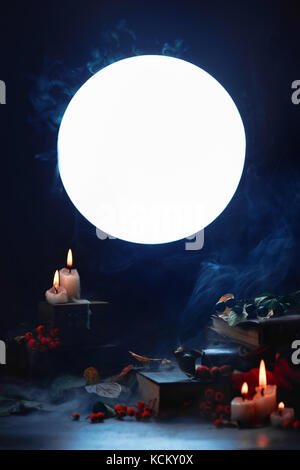 Magical books and candles in a dark still life with full moon. Halloween concept with smoke. Spooky mood. Backlight mystery scene Stock Photo