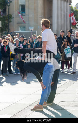 Street performer entertaining crowds in Trafalgar Square, London, England, UK, with some audience participation acrobatic stunts. Stock Photo