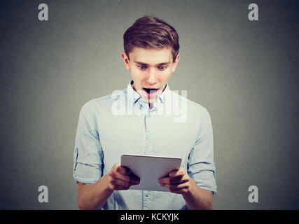 Amazed young man looking at his new tablet computer Stock Photo