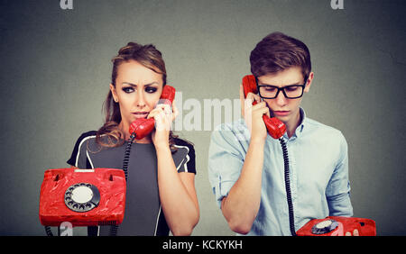 Sad confused couple man and woman talking to each other over the phone Stock Photo