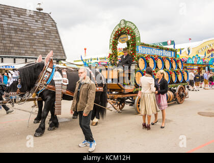 MUNICH, GERMANY - SEPTEMBER 19: People posing in front of the horses pulling beer barrels on the Oktoberfest in Munich, Germany on September 19, 2017. Stock Photo