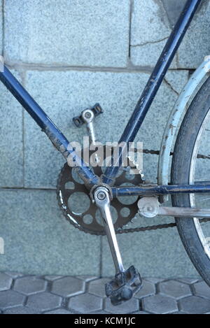 Closeup of an old blue vintage retro bicycle with pedals and chain cog against a concrete background Stock Photo