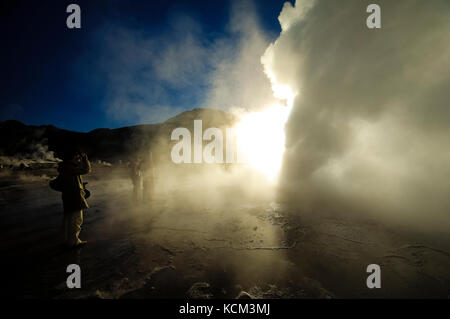 Chile Atacama Desert. Geyser del Tatio( 4.300 m.). decine di piccoli geyser, solfatare, pitte di fango e soffioni costellano questo altipiano.All'alba le colonne di vapore sono molto alte| Chile Atacama Desert tens of small geysers, fumaroles, mud pitts are all around this magnificient high plateau. At sun rise, the vapor collums are a lot higher. Waiting the sun rise while the moon sets. Stock Photo