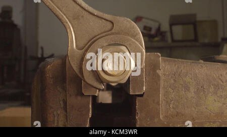 Iron Wrench in hand unscrews the large hex bolt. Wrench is tightening the chrome nut on the blue metal folding shelf. Iron Wrench in hand unscrews the large hex bolt. The wrench steel tools for repair. Stock Photo
