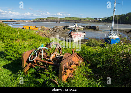 Boats and an old winch mechanism at the old harbour, Galmisdale Bay on the Isle of Eigg, Scotland, UK Stock Photo
