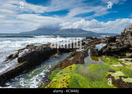 Basalt dyke rock formations on the beach at the Bay of Laig, on the Isle of Eigg, Scotland, UK.  Behind is the Isle of Rum. Stock Photo