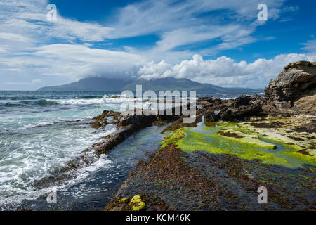 Basalt dyke rock formations on the beach at the Bay of Laig, on the Isle of Eigg, Scotland, UK.  Behind is the Isle of Rum. Stock Photo