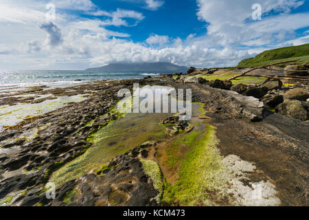 Rock formations on the beach at the Bay of Laig, on the Isle of Eigg, Scotland, UK.  Behind is the Isle of Rum. Stock Photo