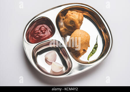 Aloo Bonda, Batata Vada or Alubonda - Indian deep fried junk but tasty food or snacks served in stainless steel plate over white background with tomat Stock Photo