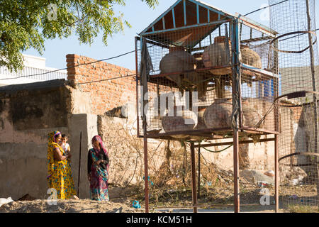 Two Indian women talking near pottery water jugs Stock Photo