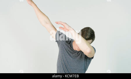 Young man makes a dab or flex it's dance move on white background Stock Photo