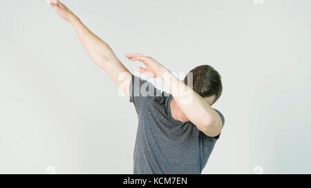 Young man makes a dab or flex it's dance move on white background Stock Photo