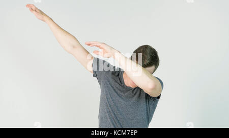 Young man makes a dab or flex it's dance move on white background Stock Photo