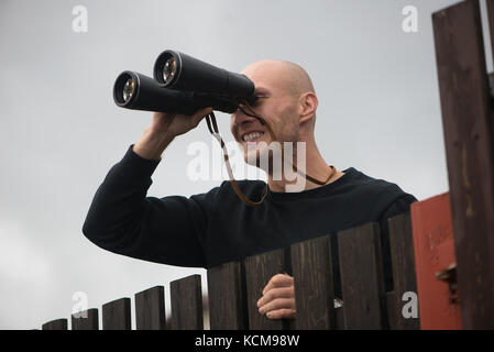 Young man looking througt binoculars Stock Photo