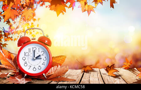 Daylight Savings Time Concept - Clock And Leaves On Wooden Table Stock Photo