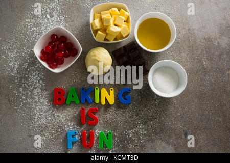 Various baking ingredients and alphabet forming baking is fun on table Stock Photo