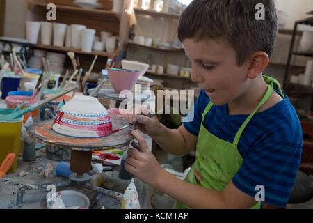 Attentive boy painting a bowl in pottery shop Stock Photo - Alamy