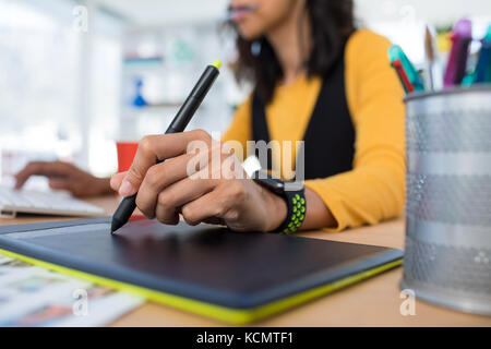 Female executive working over graphic tablet at her desk in office Stock Photo