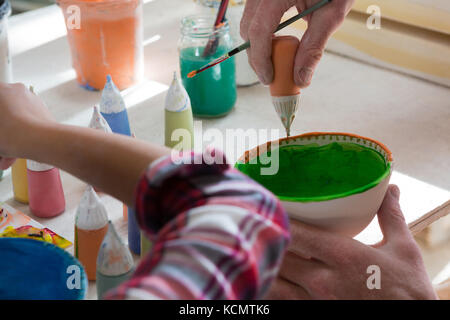 Male potter and girl painting bowl Stock Photo - Alamy
