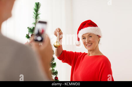 happy senior woman decorating christmas tree Stock Photo