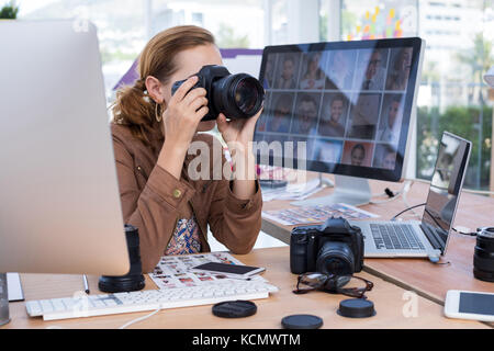 Female executive taking a photograph from digital camera in office Stock Photo