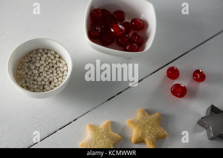 Red cherries in bowl with star shape cookies and cutter on table Stock Photo