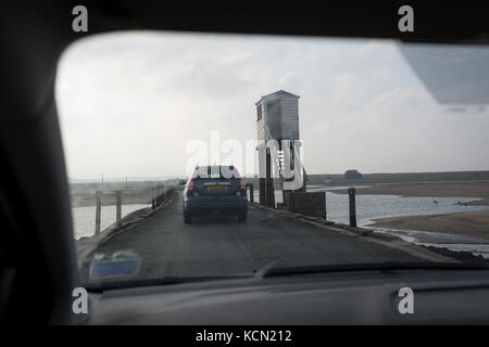 The view through a car's windscreen on the journey over the causeway between the tidal Lindisfarne island and the Northumbrian mainland, on 27th September 2017, on Lindisfarne Island, Northumberland, England. Despite tide timetables posted all over the area, drivers often mis-time their crossings, their vehicles ending up submerged in salt water. The small Lindisfarne population of just over 160 is swelled by the influx of over 650,000 visitors from all over the world every year. A tidal Island: Lindisfarne is a tidal island in that access is by a paved causeway which is covered by the North S Stock Photo