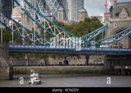 A met police officer in a police launch boat picks an item from the waters of the River Thames beneath the Victorian-era Tower Bridge with the Norman Tower of London in the capital's financial district (aka The Square Mile) behind, on 5th October, 2017, in London, England. The Gabriel Franks is a Fast Response Targa 31 boat of the Metropolitan Police Marine Policing Unit, named after the first British marine police officer to be killed in the line of duty. Stock Photo