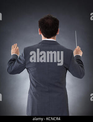 Male Orchestra Conductor Directing With Baton Over Black Background Stock Photo