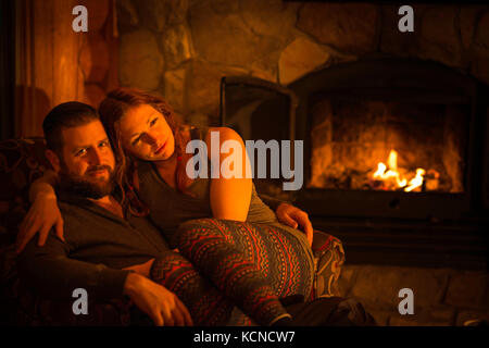Man (40) sitting by a warm open fire at a log cabin ski chalet in Mont Tremblant, Quebec, Canada Stock Photo