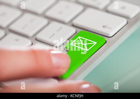 Close-up Of Hand Over Green Key With Email Sign On Keyboard Stock Photo