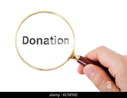 Close-up Of Hand Showing Donation Word Through Magnifying Glass Over White Background Stock Photo