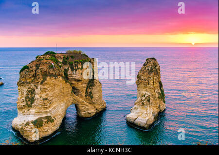 Beautiful sunset on Raouche, Pigeons' Rock. In Beirut, Lebanon.Sun and Stones are reflected in water.dense clouds in the sky. Stock Photo