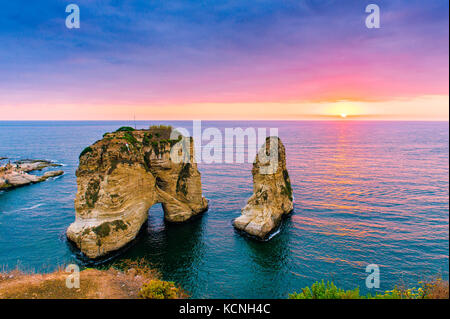 Beautiful sunset on Raouche, Pigeons' Rock. In Beirut, Lebanon.Sun and Stones are reflected in water.dense clouds in the sky. Stock Photo