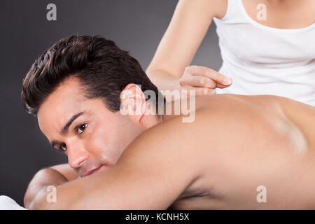 Close-up Of A Young Man Getting Acupuncture Treatment At Spa Stock Photo