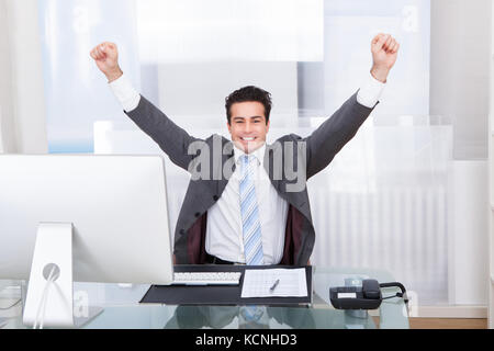 Excited Young Businessman Raising His Hands In Joy Stock Photo