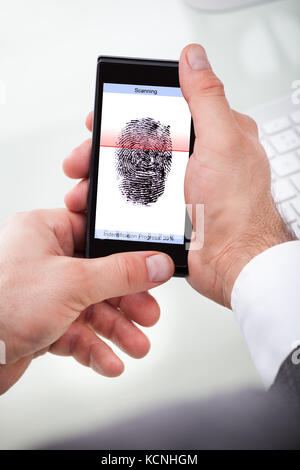 Close-up Of A Businessman Holding Cellphone Scanning Finger Stock Photo