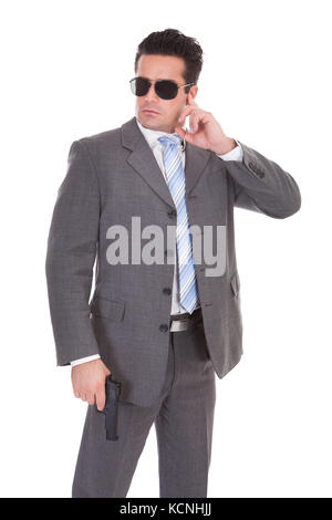 Portrait Of Young Man With Finger On Ear Holding Gun Stock Photo