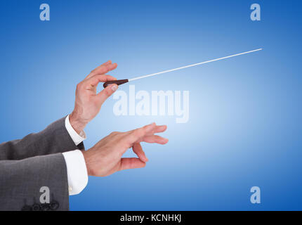 Close-up Of A Person Directing With A Conductor's Baton On Blue Background Stock Photo