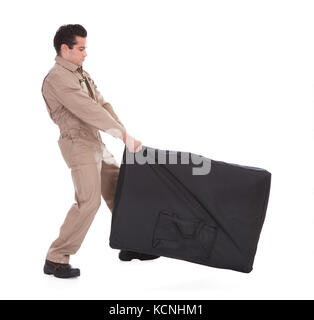Portrait Of A Male Worker Pulling Luggage Over White Background Stock Photo