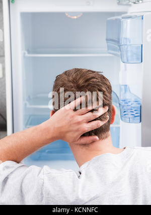 Portrait of thoughtful man looking in empty refrigerator Stock Photo