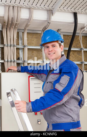 Young Worker Man With Hard Hat standing on ladder Stock Photo